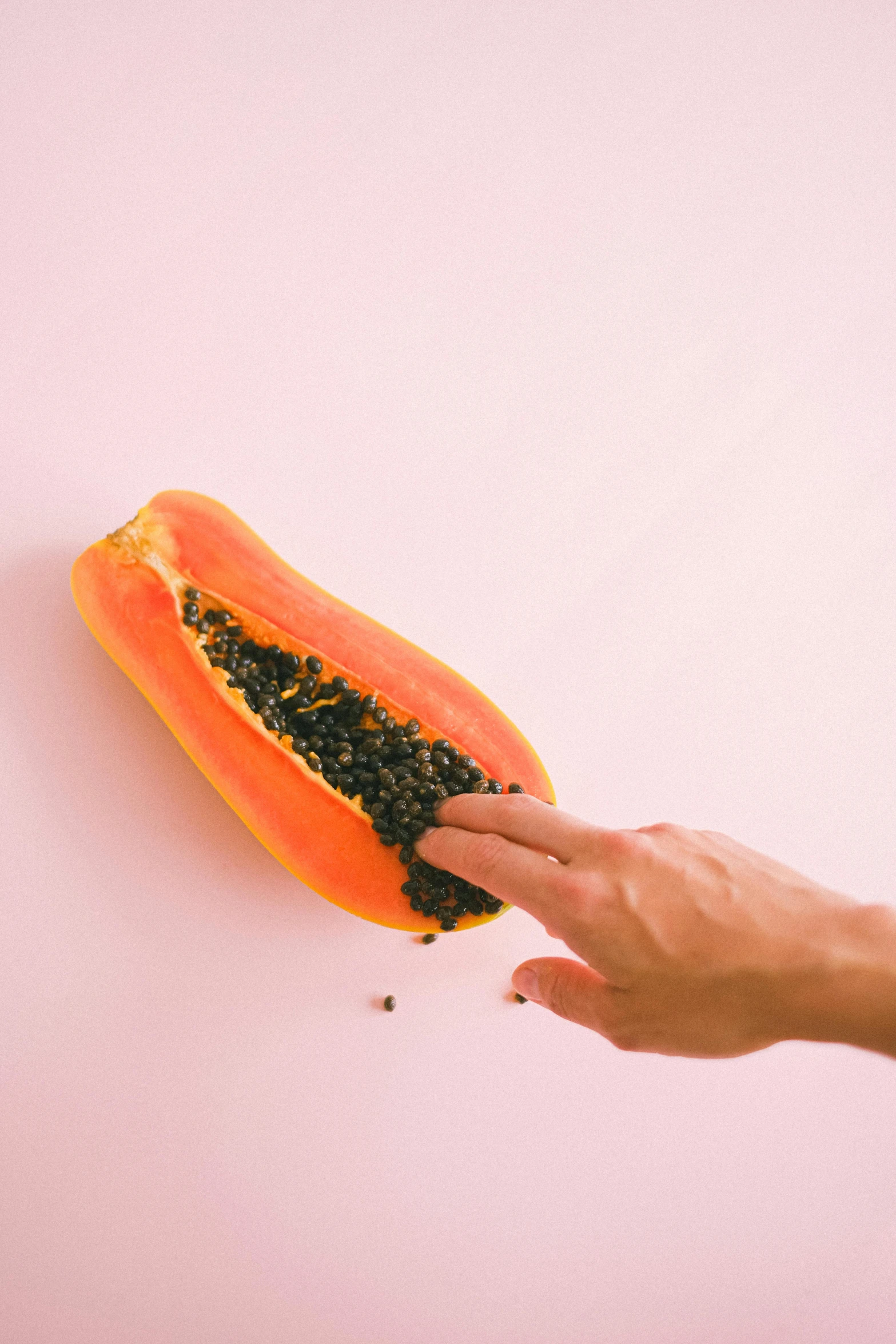 a person's hand reaching for a slice of papana, by Ryan Pancoast, trending on pexels, hyperrealism, pink and orange, huge ladybug mothership, minimalist photo, tropical fruit