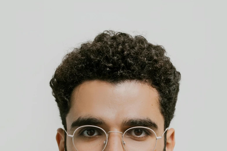 a close up of a person wearing glasses, a character portrait, trending on pexels, hurufiyya, curls on top of his head, light skin tone, middle eastern skin, perfect face template