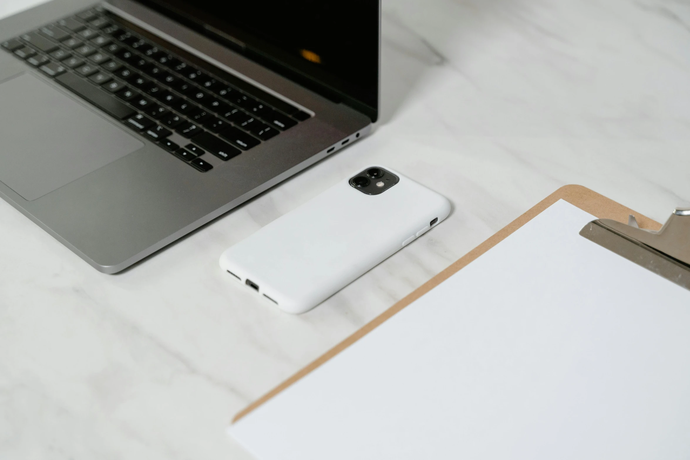 a laptop computer sitting on top of a desk next to a clipboard, trending on pexels, holding a very advance phone, matt white color armor, cell cover style, background image