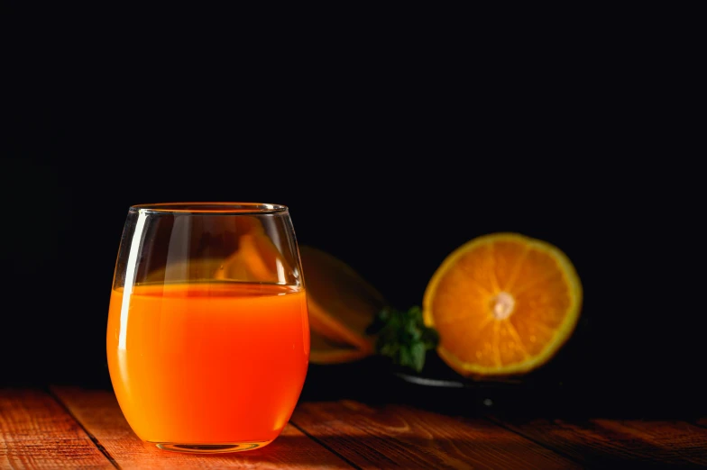 a glass of orange juice sitting on top of a wooden table, by Jan Rustem, unsplash, renaissance, background image, vibrant dark mood, vivid complementary colors, thumbnail