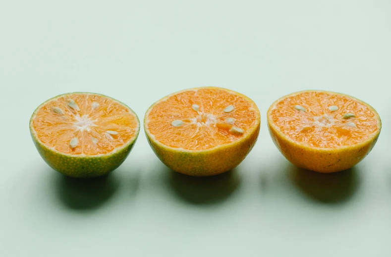 a group of oranges sitting on top of a table, by Carey Morris, trending on unsplash, on a pale background, rule of three, dividing it into nine quarters, pictured from the shoulders up