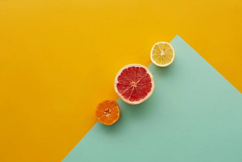 half a grapefruit, half an orange on a blue and yellow background, by Andries Stock, trending on pexels, postminimalism, red and teal and yellow, bold colored walls, on grey background, three colors