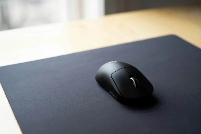 a computer mouse sitting on top of a mouse pad, inspired by Inshō Dōmoto, unsplash, minimalism, shot with sony alpha 1 camera, black canvas, no - text no - logo, gaming table