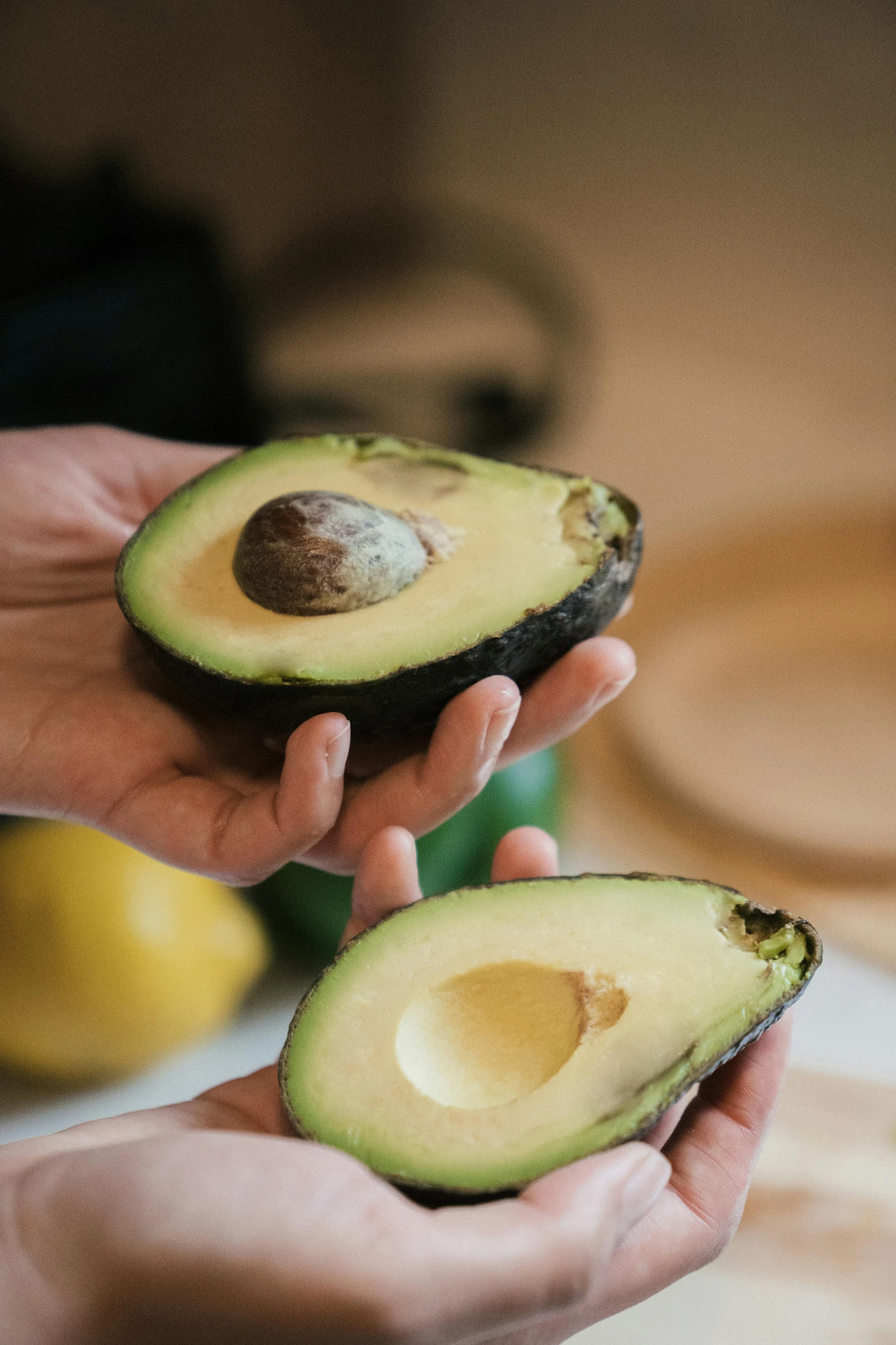 someone holding an avocado in their hands, with the fruit on the table