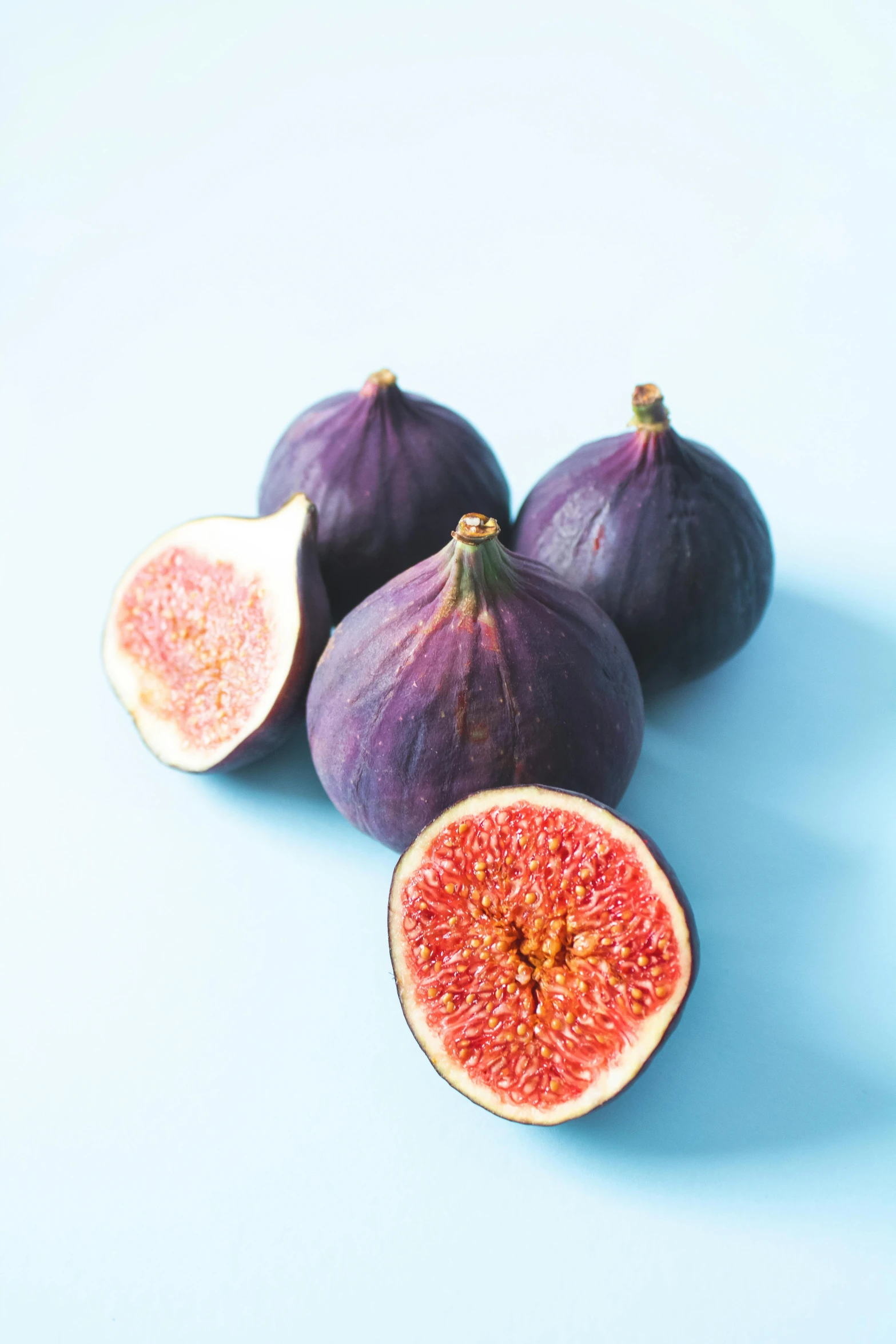 a group of figs sitting on top of a blue surface, purple and scarlet colours, 4l, petite, various sizes