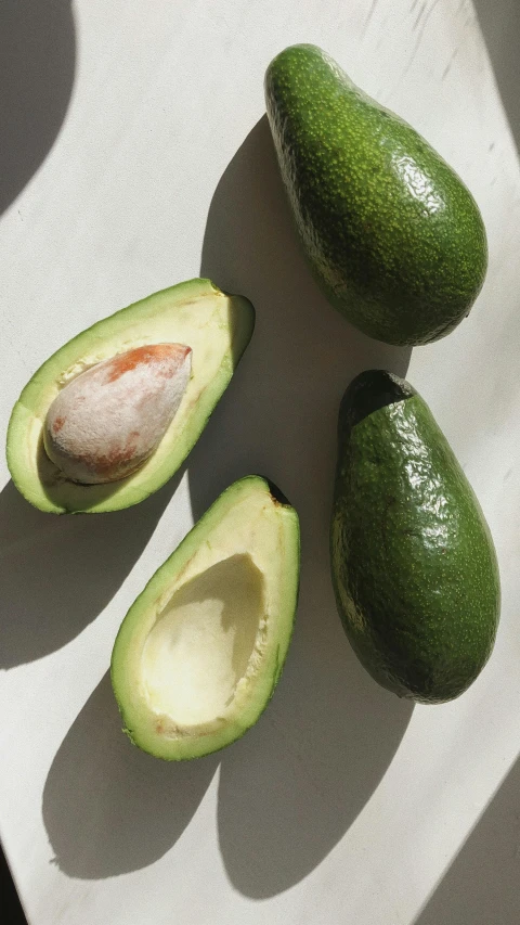 an avocado cut in half on a cutting board, a still life, pexels, taken from the high street, taken on iphone 14 pro, detailed product image, white