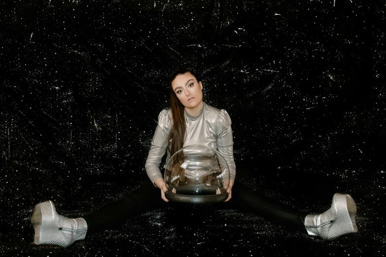 a woman sitting on the ground holding a bowl, an album cover, by Julia Pishtar, holography, giant glass dome in space, charli bowater, space suit, on black background