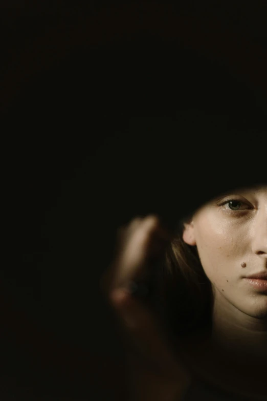 a woman looking at her reflection in a mirror, a character portrait, inspired by Jean-Jacques Henner, unsplash, dark hat, beautiful taissa farmiga, dark. studio lighting, woman with freckles