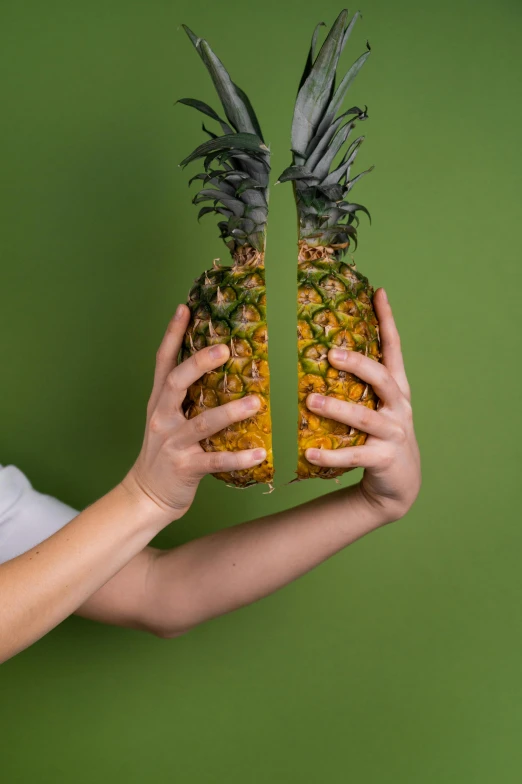 a woman holding a pineapple in front of her face, an album cover, by Adam Marczyński, pexels contest winner, image split in half, plain background, hands shielding face, cracked