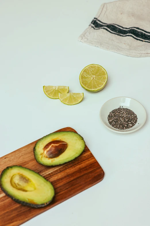 an avocado cut in half on a cutting board, pexels, hyperrealism, bowl filled with food, background image, lemon, grey