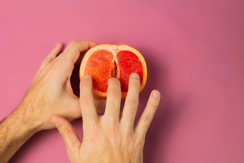 a person holding a grapefruit in front of a pink background, trending on pexels, magic realism, sitting on man's fingertip, juicy meat, slightly erotic, on grey background