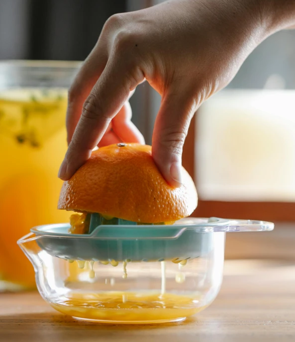 a person squeezing an orange with a juicer, thumbnail, pot, uncropped, mint