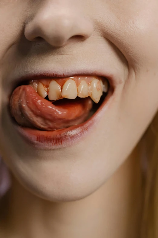 a close up of a person with a tooth, by Adam Marczyński, trending on pexels, hyperrealism, licking tongue, vampire girl, disgust, 18 years old