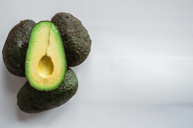 an avocado cut in half on a white surface, pexels, hyperrealism, background image