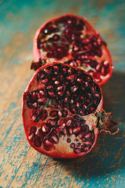 two halves of pomegranate on a wooden table, pexels, renaissance, in crimson red, made of glazed, abundant fruition seeds, 1960s-era