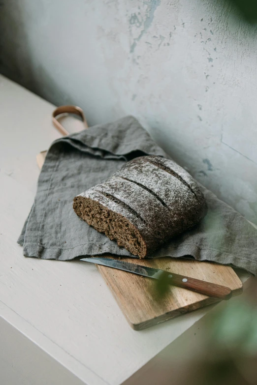 a loaf of bread sitting on top of a cutting board, inspired by Richmond Barthé, unsplash, linen canvas, dark grey, back arched, gardening