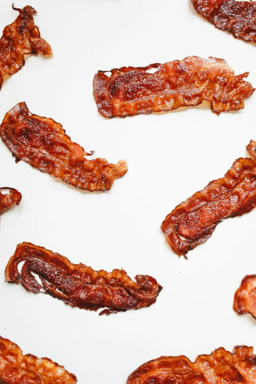 a pile of bacon sitting on top of a white table, a picture, inspired by Peggy Bacon, trending on pexels, cutout, epicurious, 6 pack, crackles