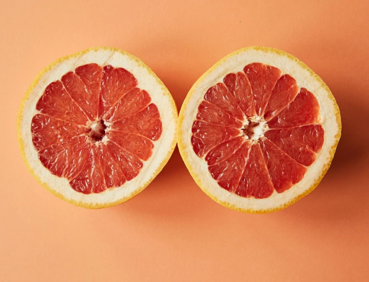 two halves of grapefruit on an orange background, by Carey Morris, trending on pexels, smooth red skin, 6 pack, on a gray background, persian queen