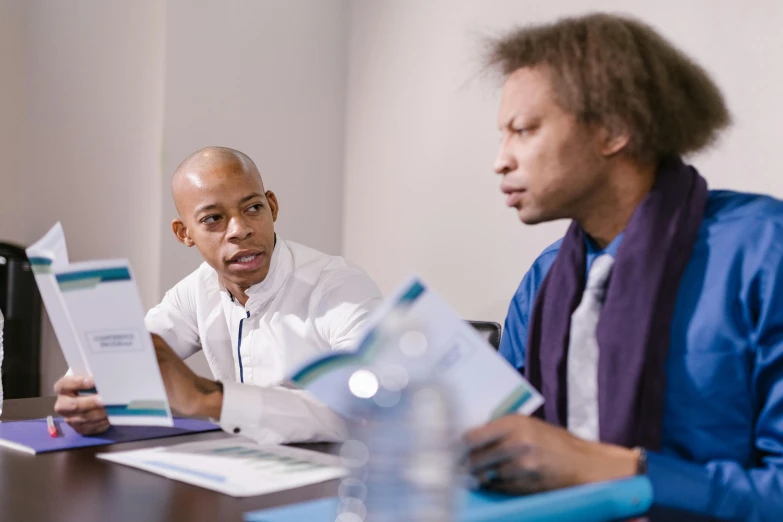 two men sitting at a table with papers in front of them, unsplash, atiba jefferson, in a meeting room, colour photograph, bowater charlie and brom gerald