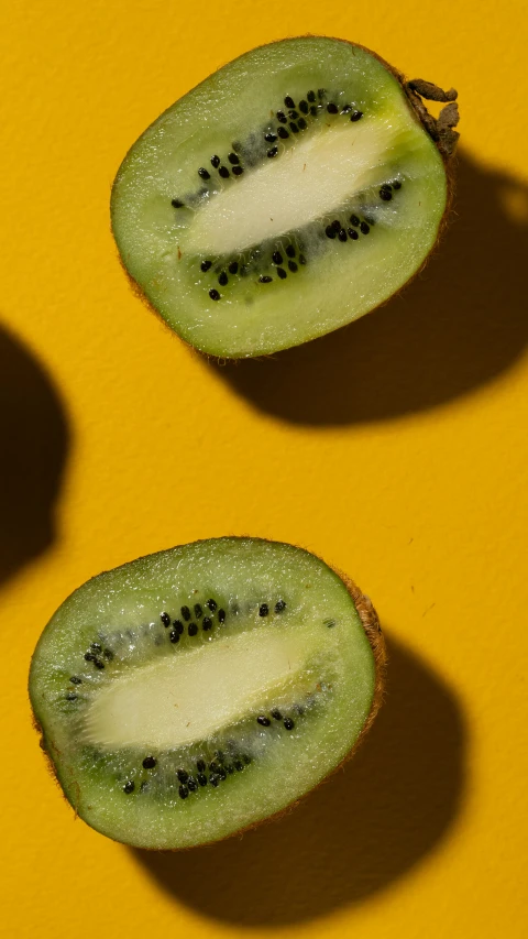 three kiwis cut in half on a yellow surface, by Carey Morris, trending on pexels, hurufiyya, #green, made of glazed, beauty shot, thumbnail