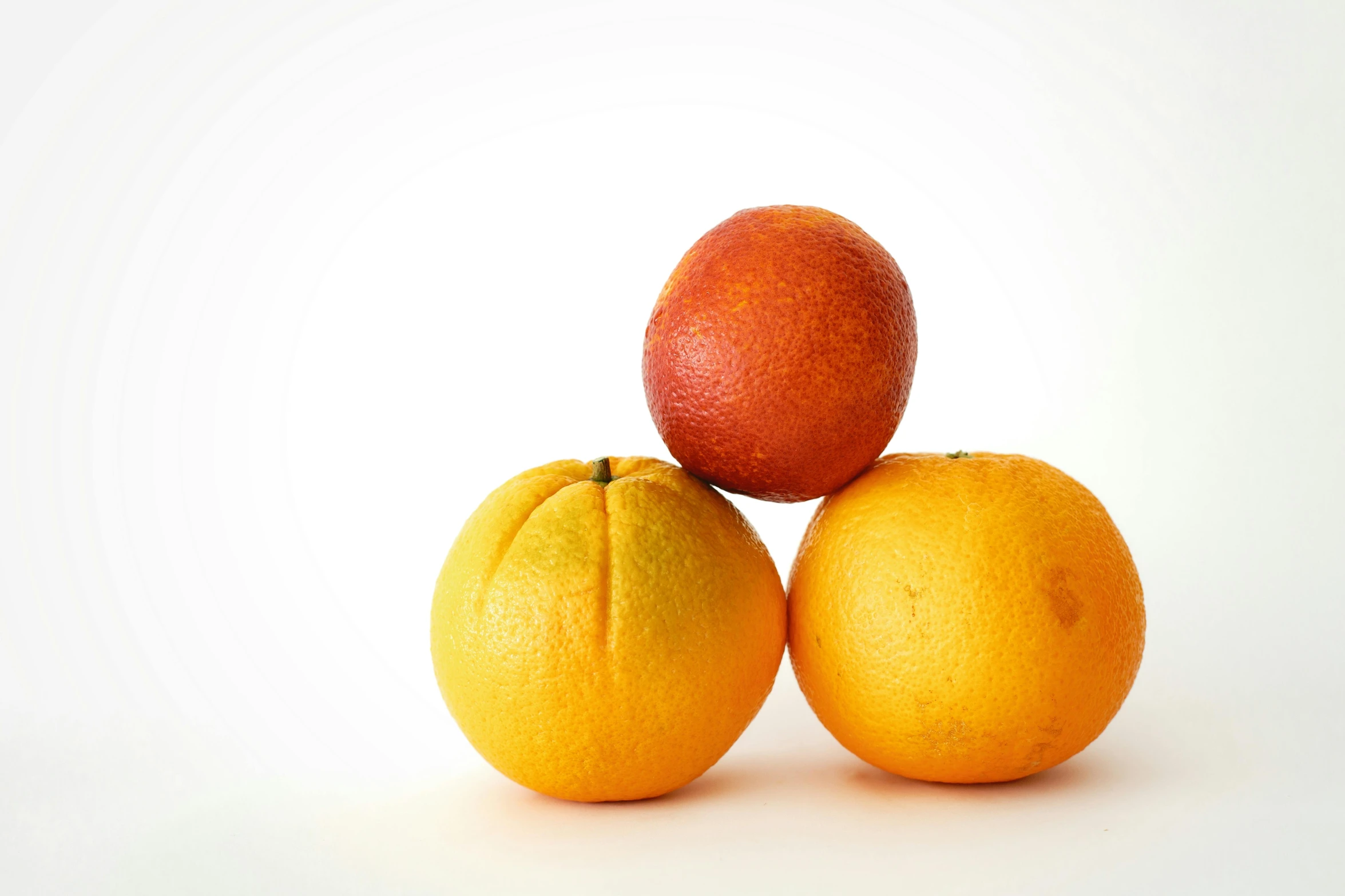 three oranges and a grapefruit on a white surface, by David Simpson, unsplash, medium format, 2000s photo, shrugging, piled around