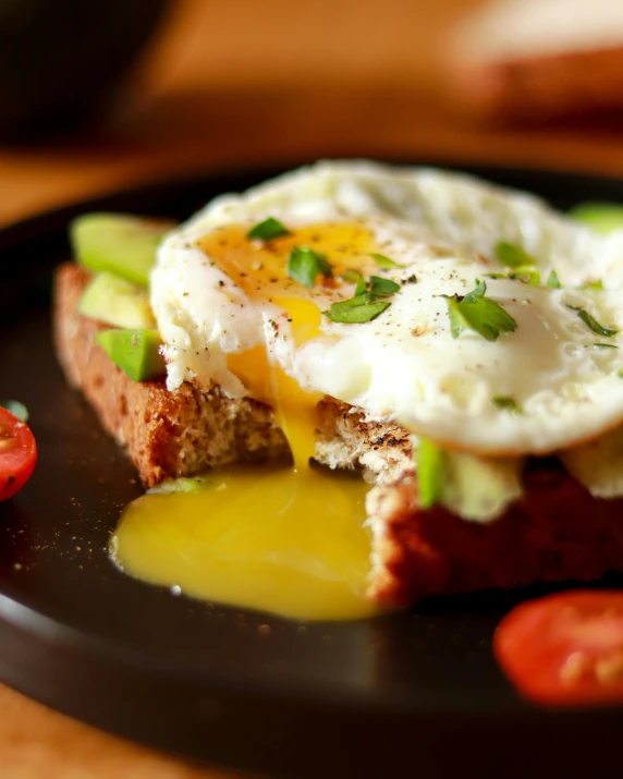 a black plate topped with an egg and avocado, toaster, profile image, beutiful, brown