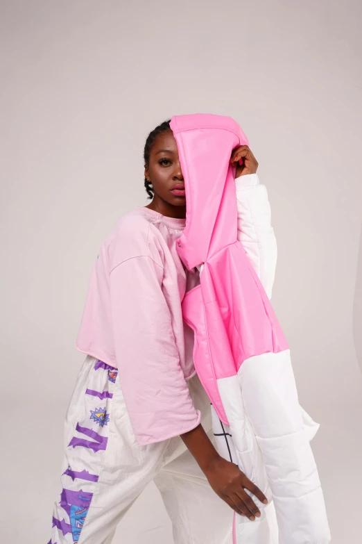 a woman in a pink jacket and white pants, an album cover, by Dulah Marie Evans, unsplash, happening, wearing an oversized hoodie, wrapped arms, white background, half and half