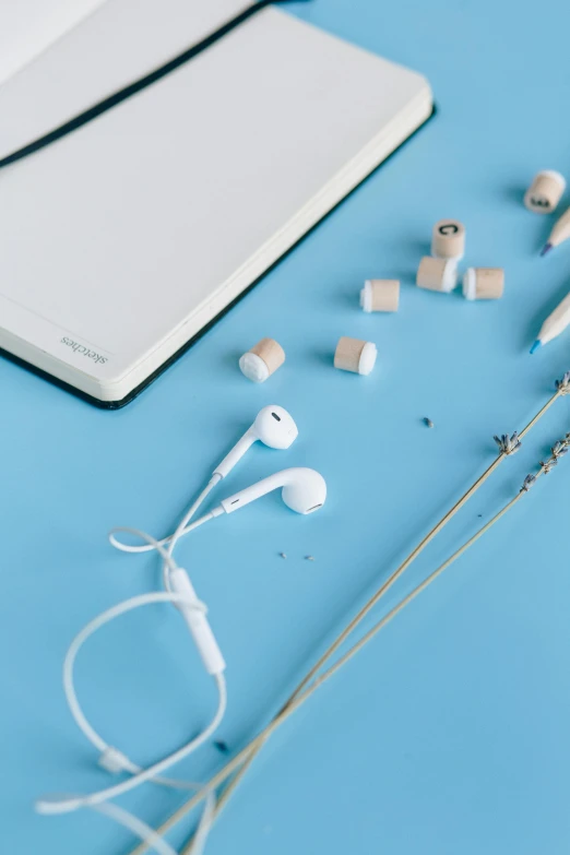 headphones and a notebook on a blue surface, an album cover, by Andries Stock, trending on pexels, earbuds jewelry, knolling, white, 15081959 21121991 01012000 4k