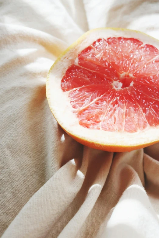 a close up of a person holding a grapefruit, inspired by Elsa Bleda, renaissance, someone sits in bed, linen, food, flirtatious