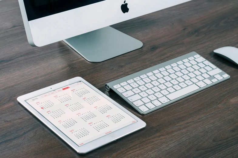 a desktop computer sitting on top of a wooden desk, by Carey Morris, trending on unsplash, female calendar, using a magical tablet, knolling, apple design