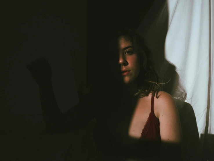 a close up of a person in a dark room, inspired by Elsa Bleda, posing in a bedroom, some sunlight ray, behind red curtains, instagram post