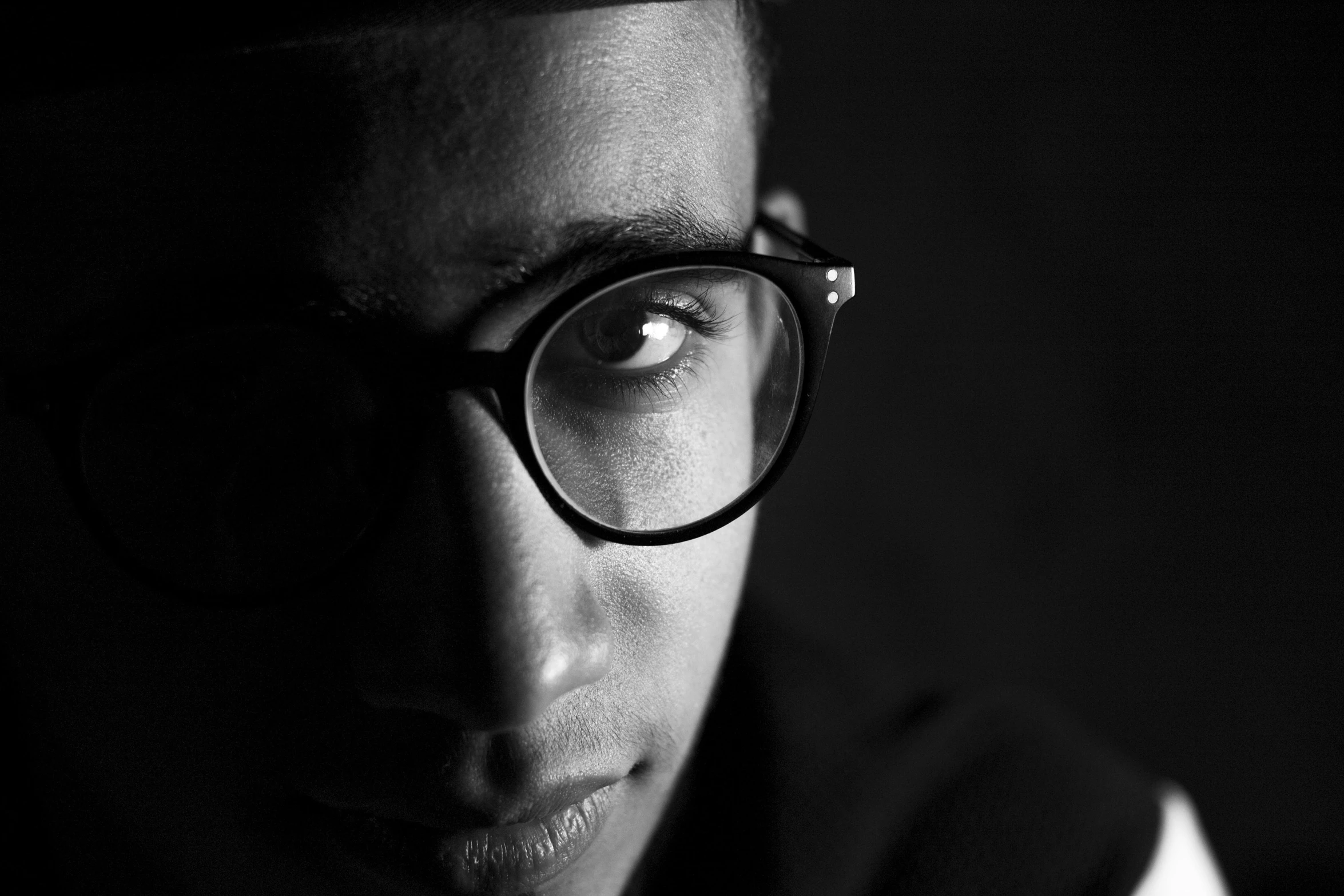 a black and white photo of a man wearing glasses, unsplash, visual art, ashteroth, moody dim lighting, taken in the late 2000s, with square glasses