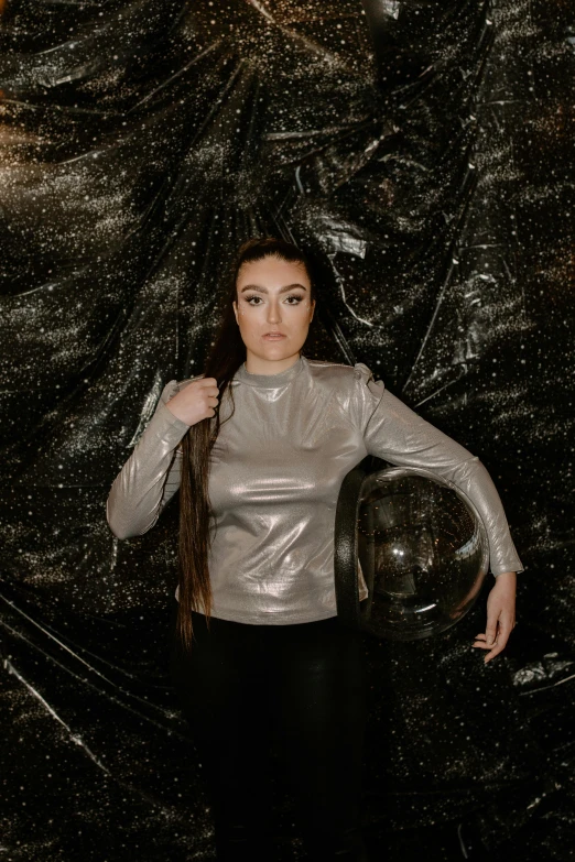 a woman is posing with a motorcycle helmet, an album cover, inspired by Eve Ryder, pexels contest winner, holography, in a space starry, sasha grey, vantablack wall, wearing a turtleneck and jacket