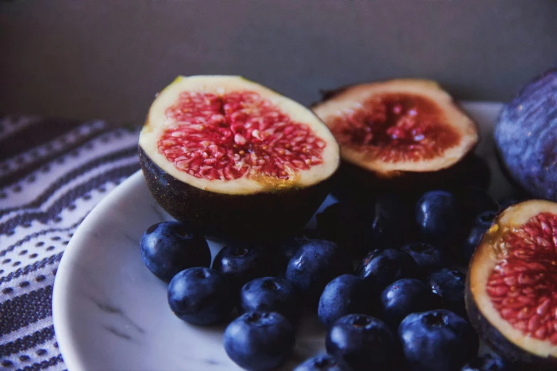 a white plate topped with figs and blueberries, a photo, by Carey Morris, pexels contest winner, hyperrealism, 🦩🪐🐞👩🏻🦳, natural morning light, black, avatar image