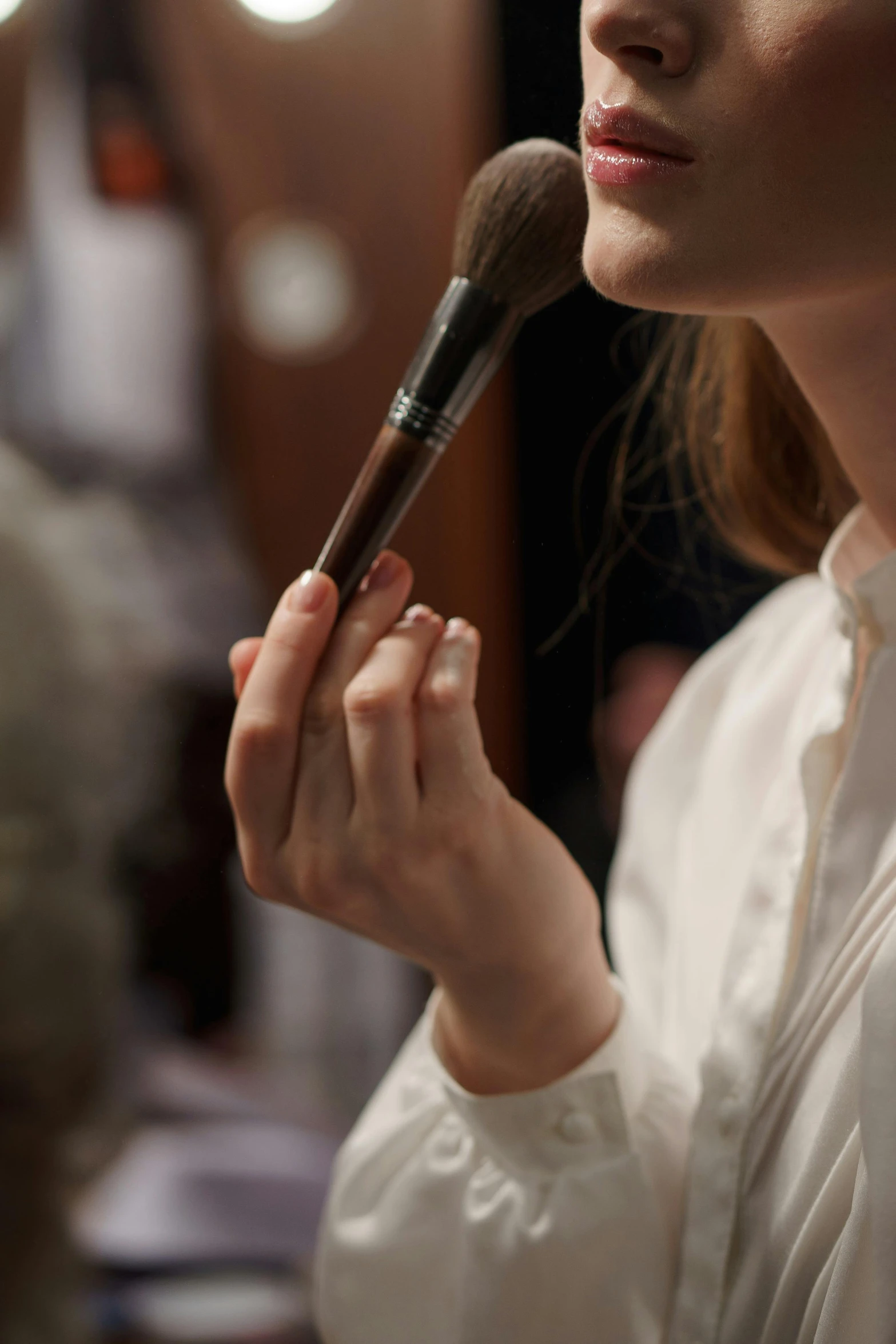 a woman holding a makeup brush in front of her face, by David Simpson, photorealism, fashion week backstage, jaquet droz, hammershøi, close - up profile