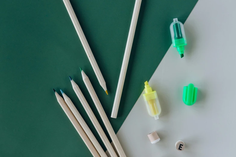 a group of pencils sitting on top of a table, a child's drawing, inspired by Art Green, trending on pexels, white neon details, knolling, green and white, jade green