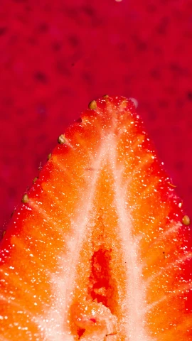 a close up of a sliced strawberry against a red background, a macro photograph, inspired by Jacopo Bellini, pexels, made of glazed, pear, strawberry granules, full frame image