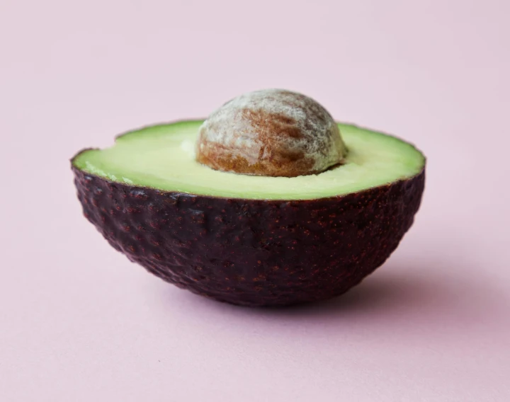 an avocado cut in half on a pink surface, trending on pexels, halo halo halo halo 8k, epicurious, olive skin, shot on hasselblad