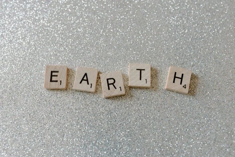 the word earth spelled with scrabbles on a shiny surface, unsplash, ((rocks)), silver，ivory, etsy, 💋 💄 👠 👗
