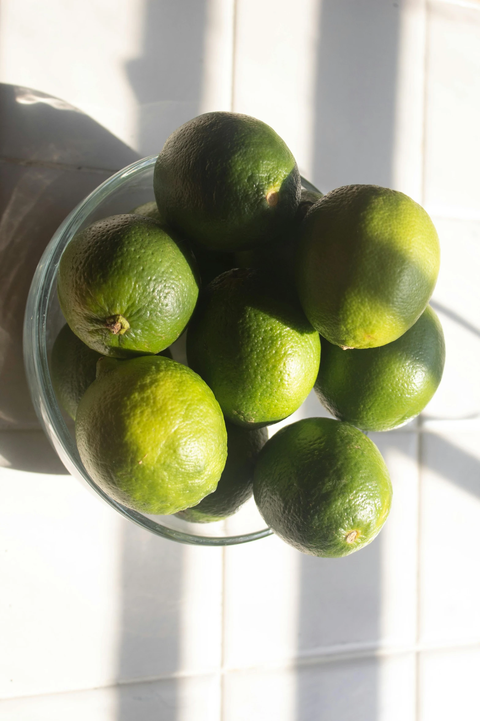 a glass bowl filled with limes on top of a counter, view from ground level, highly upvoted, slightly sunny, passion fruits