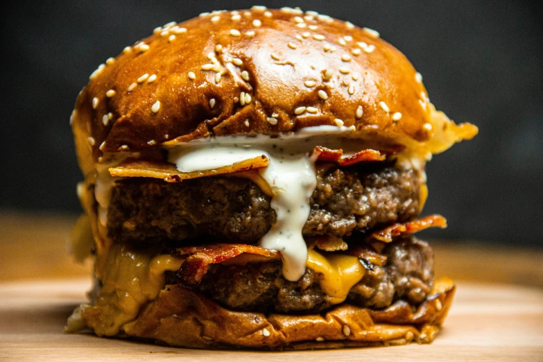 a hamburger sitting on top of a wooden table, profile image, cheese and pepperoni, up close, buzzed sides