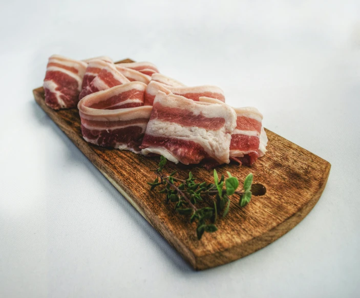 a wooden cutting board topped with slices of bacon, unsplash, mutton chops, 6 pack, 3 / 4 view, herbs