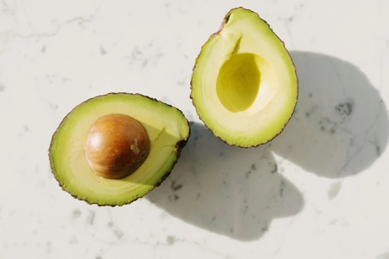 an avocado cut in half on a table, trending on pexels, on a marble pedestal, sustainable materials, highly upvoted, olive