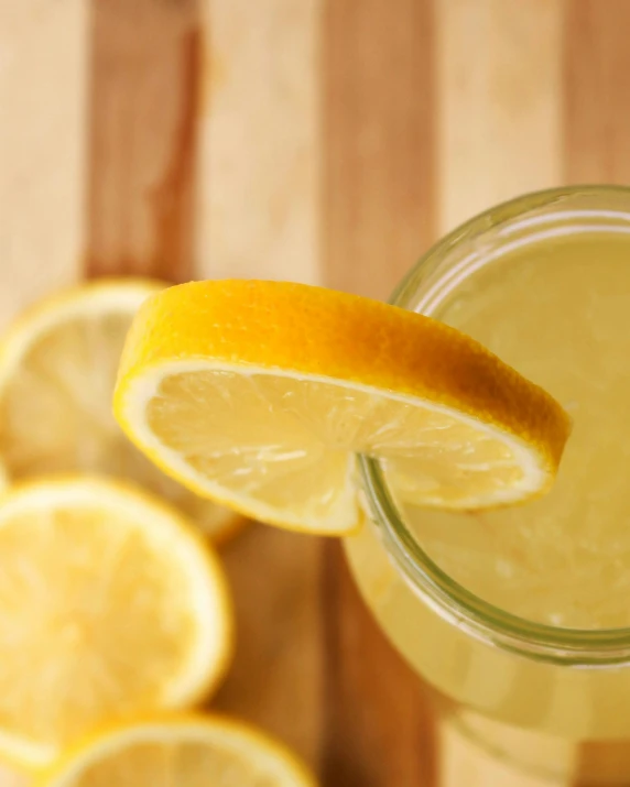 a glass of lemonade sitting on top of a wooden table, promo image, zoomed in, zoomed out, mead