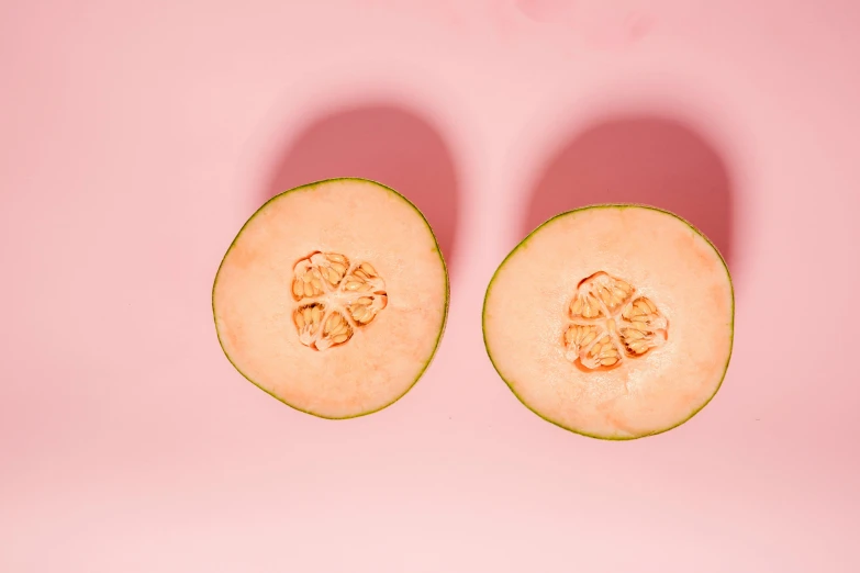 two halves of a melon on a pink surface, by Olivia Peguero, trending on pexels, natural skin tones, background image, pear, 5k