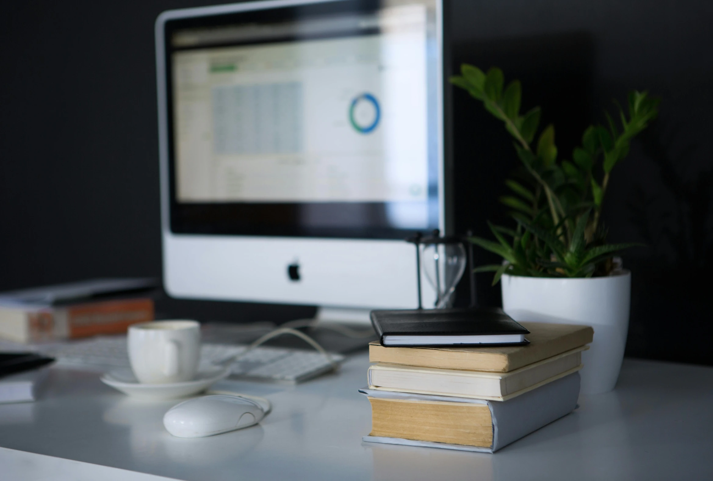 a computer monitor sitting on top of a white desk, by Robbie Trevino, trending on unsplash, stack of books on side table, power bi dashboard, close up portrait shot, high quality photo