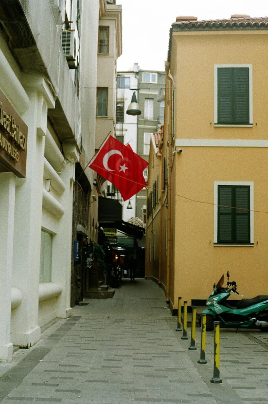 a motor scooter parked on the side of a narrow street, inspired by Géza Mészöly, flags, turkey, 1999 photograph, harbor