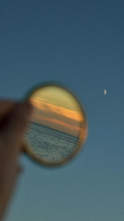 a person looking at the moon through a magnifying lens, a picture, by Nathalie Rattner, unsplash, photorealism, seaview, mirrors, color photograph, oceanside