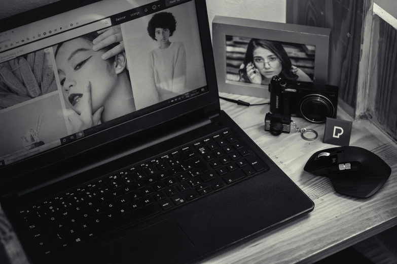 a laptop computer sitting on top of a wooden desk, a black and white photo, inspired by Elsa Bleda, modeling studio, looking at camera, pc screen image