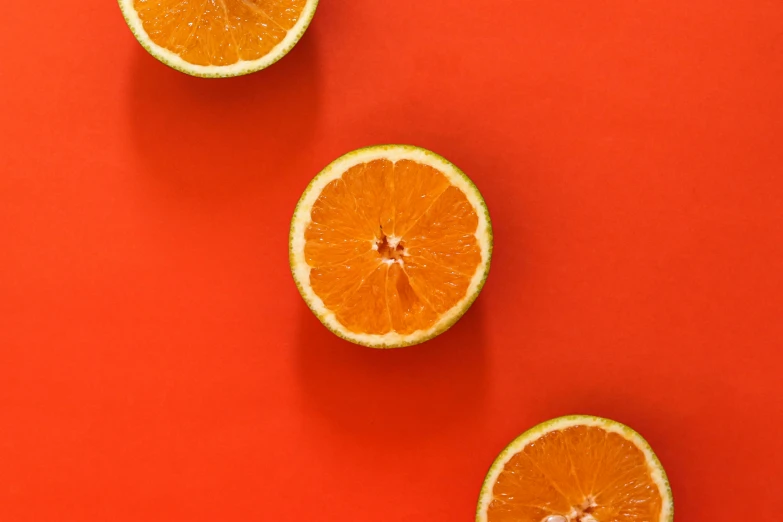 a group of oranges sitting on top of a red surface, trending on pexels, background image, rule of three, 🍸🍋, minimalist wallpaper